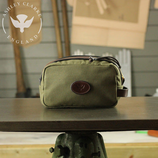 green waxed canvas wash bag by Ashley Clarke England on top of a table