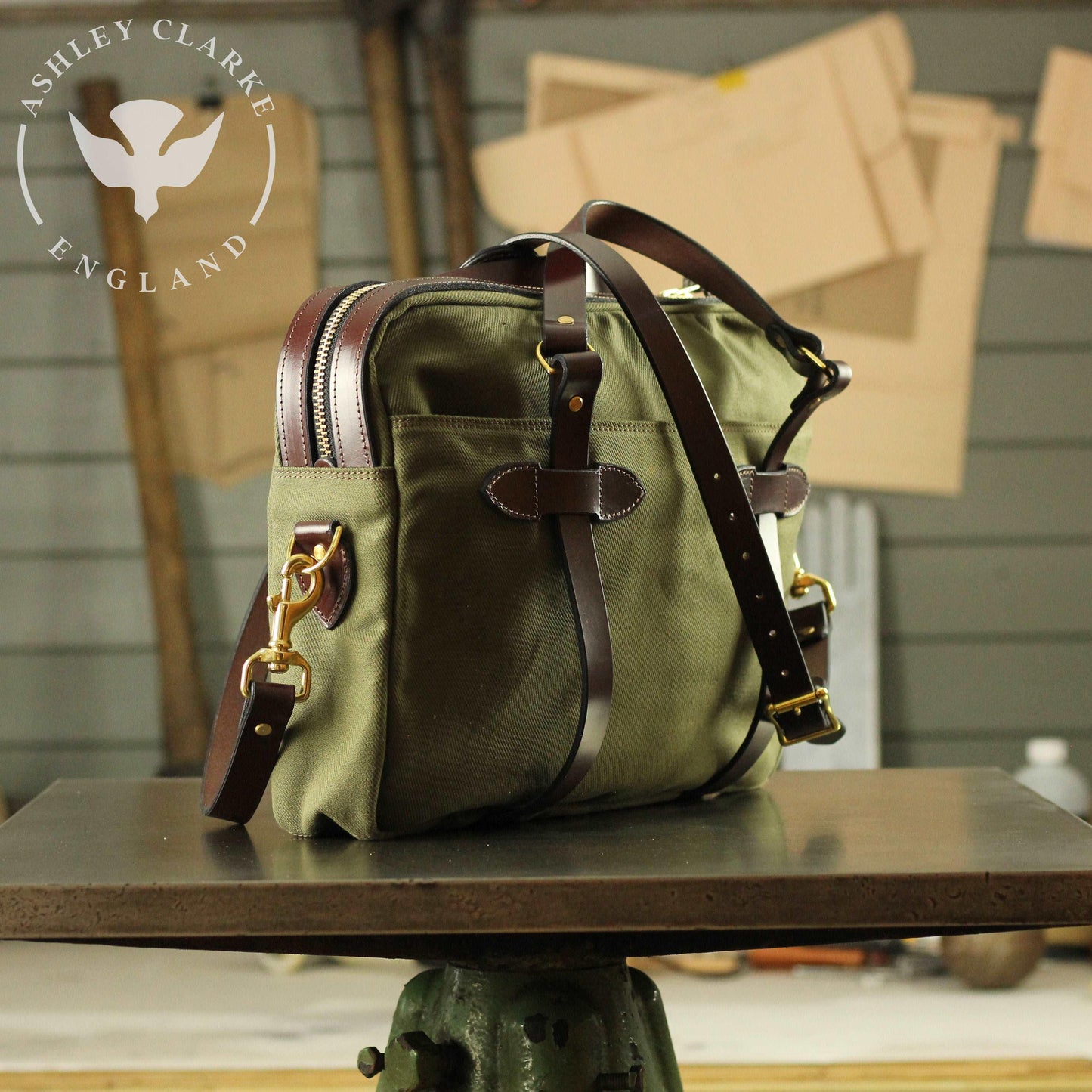 back side view of a green waxed canvas briefcase laptop bag by ashley clarke on a table