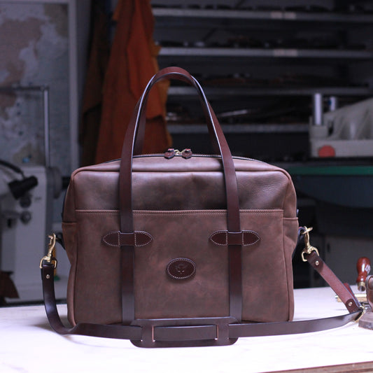 Brown leather weekender bag on a workbench